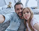 Padre e figlia si scattano un selfie giocoso, un'immagine che cattura la gioia del loro rapporto padre-figlia, quasi come in un'interpretazione freudiana della felicità.