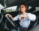 Kobieta za kierownicą zastanawia się, czy OC przedłuża się automatycznie. Widok na morze i palmy.