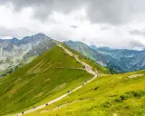 Szlak turystyczny wiodący przez zielone zbocza, prowadzący do skalistych szczytów. To widok na najpiękniejsze góry w Polsce, Tatry.