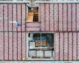 Siatka rur do ogrzewania podłogowego ułożona co 10-15 cm na betonowej płycie fundamentowej. Widoczne schody i materiały budowlane.