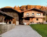 Maso Gallo Rosso: un'accogliente casa in legno e un fienile rustico immersi nel paesaggio alpino al tramonto.