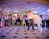 Para młoda wiruje w tańcu, goście patrzą z zachwytem. To piękny moment, jak bachata taniec.