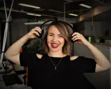 Uśmiechnięta kobieta w słuchawkach, gotowa do nagrania podcastu po angielsku.