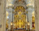 Prunkvoller Altar im Kathedrale Sevilla Innenraum, verziert mit goldenen Skulpturen und Malereien, die eine himmlische Szene darstellen.