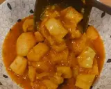 Un plato de papas con choco en una salsa naranja, servido en un cuenco con un patrón de puntos.