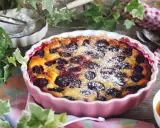 Un délicieux clafoutis aux prunes, saupoudré de sucre glace, prêt à être dégusté.
