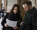 Kobieta i prawnik w todze analizują dokumenty. Może to dotyczyć sprawy o grzywnę lub inne kwestie prawne.