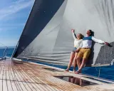 Un couple heureux profite du soleil sur un voilier. Ils semblent avoir fait le bon choix en décidant de choisir un voilier pour leurs vacances.