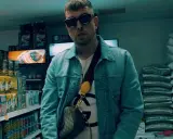 Malik Sentino w okularach i dżinsowej kurtce stoi w sklepie, otoczony towarem.