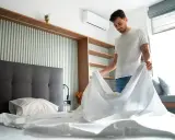 Hombre cambiando sábanas, un paso clave para saber como quitar acaros del colchon y mantener un ambiente fresco y saludable.
