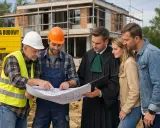 Inwestorzy, prawnik i budowlańcy omawiają projekt domu. Nowelizacja prawa budowlanego może wpłynąć na ich plany.