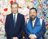 Two billionaire art collectors, Bernard Arnault and Takashi Murakami, pose in front of Murakami's signature smiling flower art.