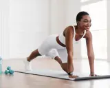 Frau in weißer Sportkleidung macht Liegestütze zu Hause. Ideal für Muskelaufbau Frau ab 60 zu Hause.