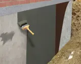 Aplicación de membrana para impermeabilizar pared exterior. Se ve una brocha aplicando material sobre el muro de concreto, seguido de una capa protectora y tierra.