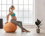 Kobieta w zaawansowanej ciąży wykonuje ćwiczenia na piłce. Dba o formę i dobre samopoczucie podczas oczekiwania na dziecko.
