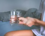 Drżąca ręka trzyma szklankę wody. Objawy mogą wskazywać na atak padaczki alkoholowej. Co robić?
