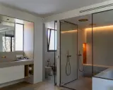 Moderno baño con ventana, ducha de cristal, bañera y lavabo doble.