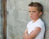 Niño con brazos cruzados y expresión desafiante. La esperanza es que el trastorno negativista desafiante se cura con apoyo.