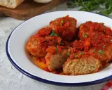 Polpette di pane succulente in salsa di pomodoro, guarnite con prezzemolo fresco. Un piatto casalingo che profuma di tradizione.
