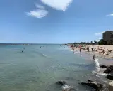 Sonniger bari strand mit vielen Menschen, die im Meer schwimmen und sich am Sand sonnen.