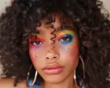 Un rostro con un vibrante maquillaje de ojos arcoíris y purpurina, celebrando la diversidad y el orgullo.