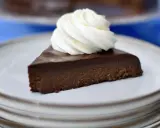 En bit fransk chokladtårta med en virvel av vispad grädde på en tallrik.