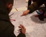 Menschen diskutieren auf einer Karte, die Details der Stadt zeigt. Sie planen die monitoring soziale stadtentwicklung, markieren Bereiche und nutzen ein Smartphone.
