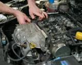 Mechanik pracuje przy silniku, wymieniając czujnik położenia wałka rozrządu.