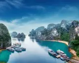 Widok na zatokę Ha Long w Wietnamie z łodziami i skalistymi wyspami.