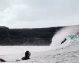 Surfer wartet auf die perfekte Welle vor einer Felswand, um Costa Calma surfen zu gehen.