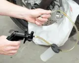 Ręce majsterkowicza odkręcają odpowietrznik zacisku hamulcowego, przygotowując się do tego, jak wymienić płyn hamulcowy w motocyklu.