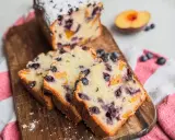 Saftiger Joghurt Kuchen mit Blaubeeren und Pfirsichstücken, bestäubt mit Puderzucker.