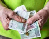 Dłonie trzymają polskie banknoty. Może to być pomoc z MOPS, np. renta socjalna.