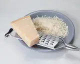 Kawałek sera i tarta masa na talerzu, obok tarka. Szukasz, czym zastąpić parmezan?