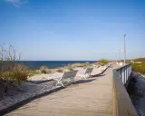 Drewniana promenada w Dziwnowie z ławkami i widokiem na morze. Idealne miejsce na spacer i podziwianie atrakcji nadmorskich.