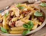 Penne z kurczakiem i suszonymi pomidorami, ozdobione świeżą bazylią. Pyszne danie, które zachwyci każdego smakosza.