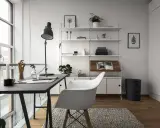 Ett modernt hemmakontor med ett mörkt skrivbord, en vit stol och en stilren, inredd bokhylla. Ljuset flödar in från stora fönster.