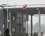 Grön trafiksignal vid gränsövergången Joensuu, Finland. Snö faller över byggnaden och träden. En polisbil syns. Gränsen mellan Ryssland och Finland är stängd.