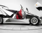 Silberner Lotec C1000 Supersportwagen mit geöffneten Türen und Hauben, rote Sitze und sichtbarer Motor.