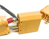 Löten eines roten Kabels an einen goldenen XT90-Stecker. Ein weiterer Stecker liegt daneben.