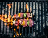 Brochetas de carne y verduras sobre parrilla de carbón, llamas naranjas. ¡Así se hace barbacoa carbón!