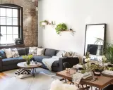 Sofá gris, mesa de centro redonda, mesa de comedor de madera y espejo de cuerpo entero crean un ambiente de **estilo cozy**.