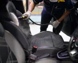 Un profesional usa vapor para limpiar los asientos del coche, mostrando cómo limpiar los asientos del coche de forma efectiva.