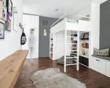 Ein weißes Hochbett mit integrierten Regalen und Stauraum bietet viele Ideen unterm Hochbett für Spielzeug und Bücher. Ein Holzbalken und ein Kuhfell-Teppich ergänzen den Raum.