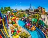 Parque acuático colorido con atracciones para niños en Cracovia. Barcas navegan por un río azul rodeado de juegos y vallas vibrantes.