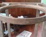 Estructura de madera de un palanganero antiguo, lista para restaurar. Se aprecian sus patas y el aro superior curvo.
