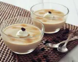 Deux coupes de **dessert au café** onctueux, garnies de crème fouettée et d'un grain de café, sur un napperon tressé.
