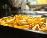 Une plaque de frites au four dorées et fumantes, prêtes à être dégustées.