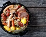 Choucroute garnie, un plat emblématique des alsace spécialités culinaires, avec saucisses, viandes et pommes de terre dans une cocotte.