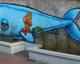 Niebieski wieloryb z grzybkiem na grzbiecie. Inspiracja, jak zrobić mural na kartce, w miejskim krajobrazie.